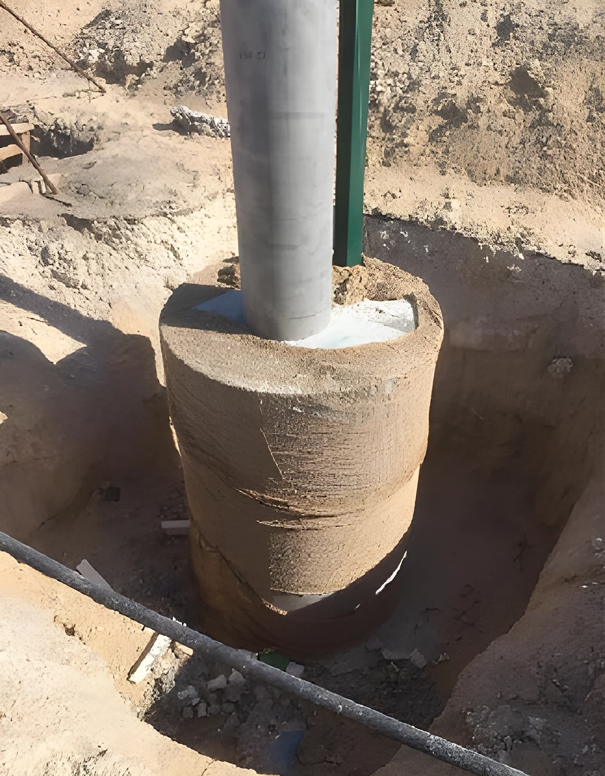 A fence post set in its cast concrete footing